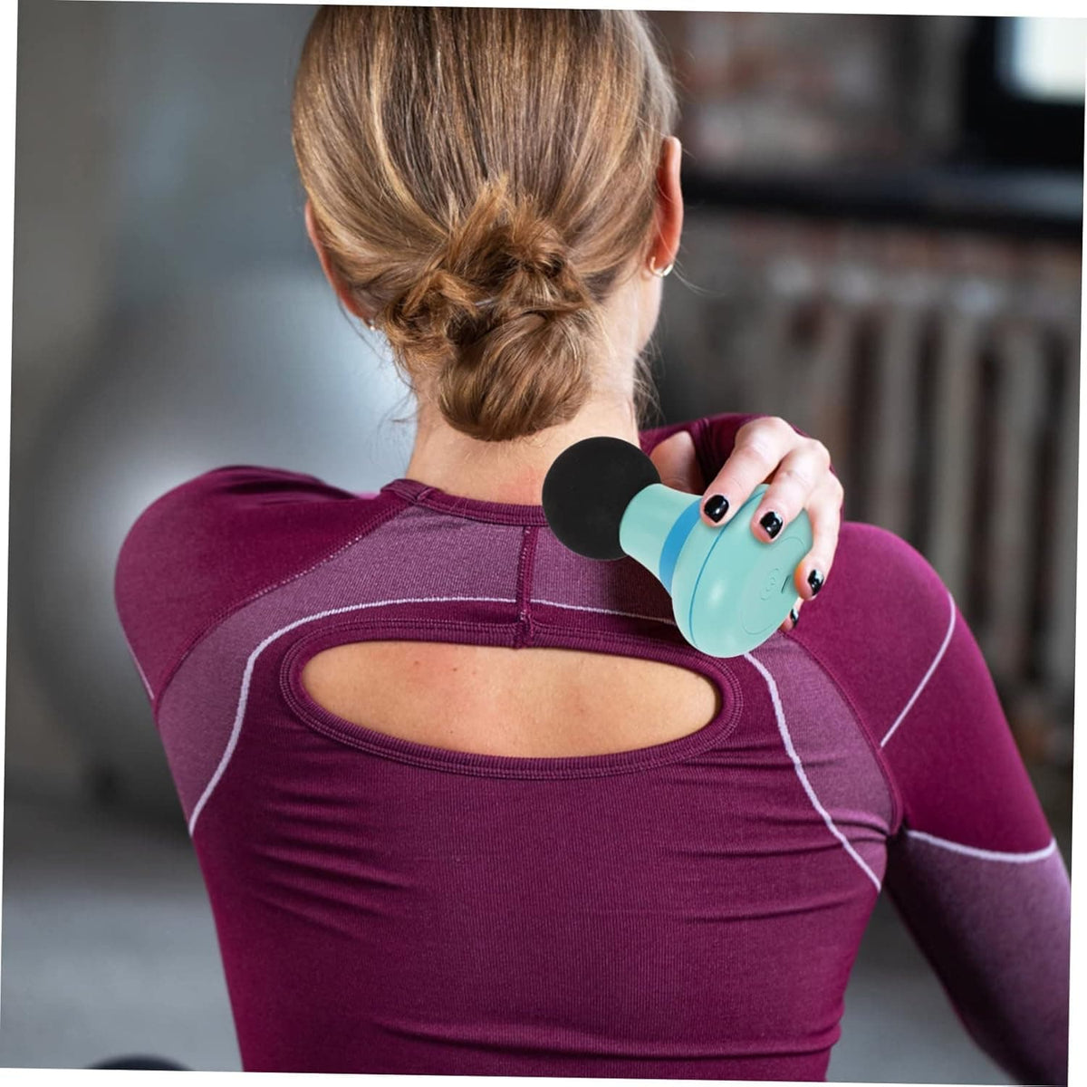Mini appareil de massage pour cervicale – vue de dos d'une personne utilisant l'appareil sur l'épaule, couleur bleu pastel, design élégant et compact
