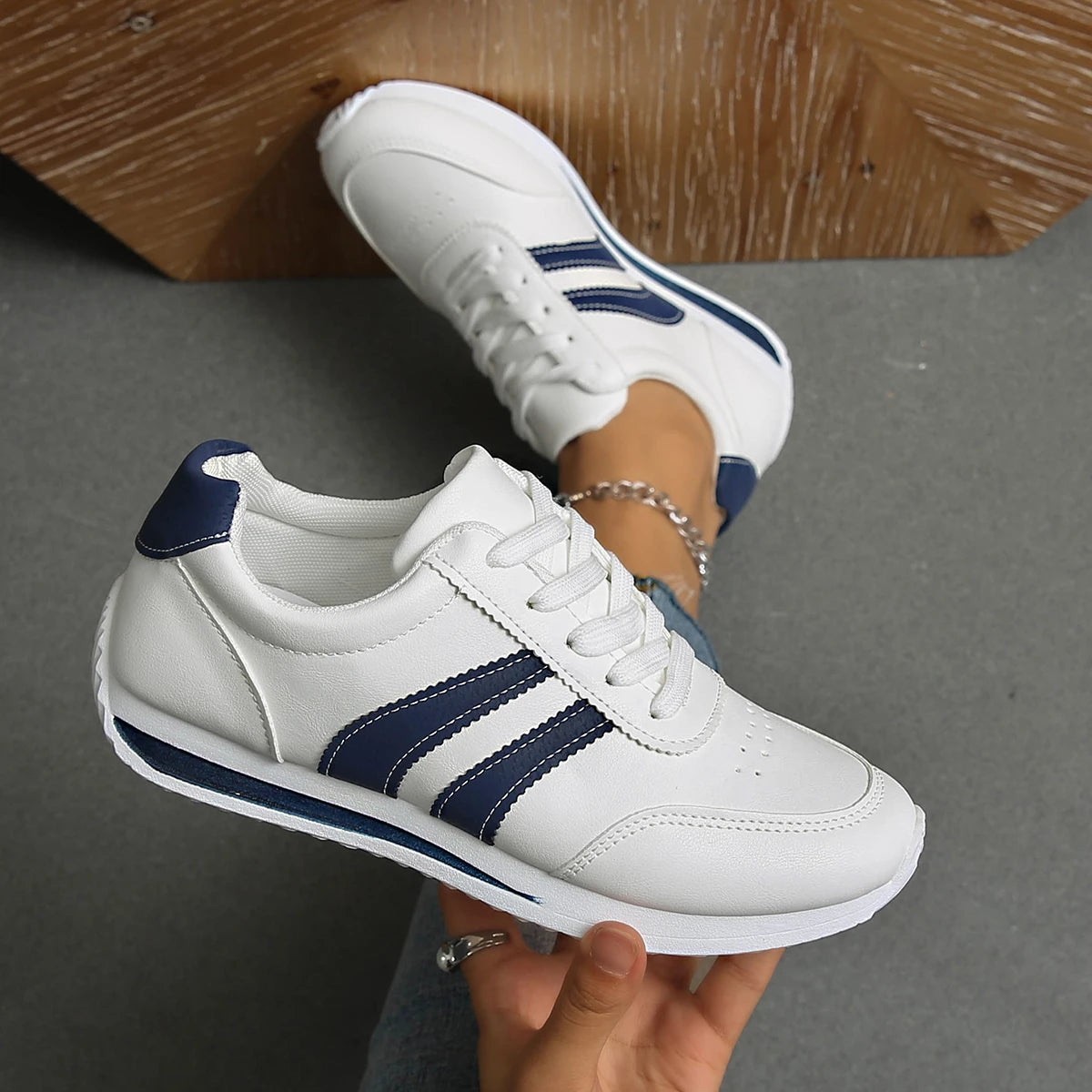 Basket orthopédique femme blanches avec rayures navy, vue de près, portées avec un jean, mettant en avant le confort et le style.