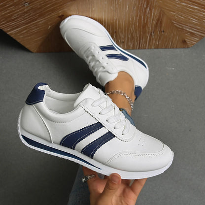 Basket orthopédique femme blanches avec rayures navy, vue de près, portées avec un jean, mettant en avant le confort et le style.