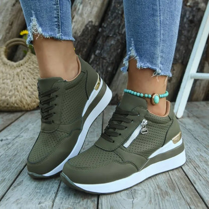 Basket orthopédique femme - Sneakers légères vert olive à semelle épaisse, avec zip et détails dorés, portées avec un bracelet turquoise.