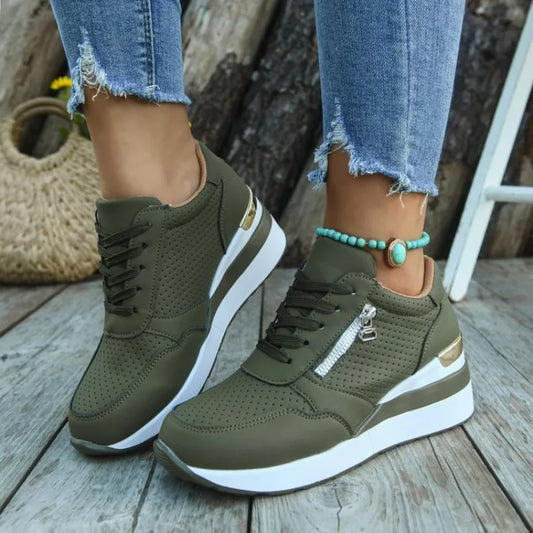 Basket orthopédique femme - Sneakers légères vert olive à semelle épaisse, avec zip et détails dorés, portées avec un bracelet turquoise.
