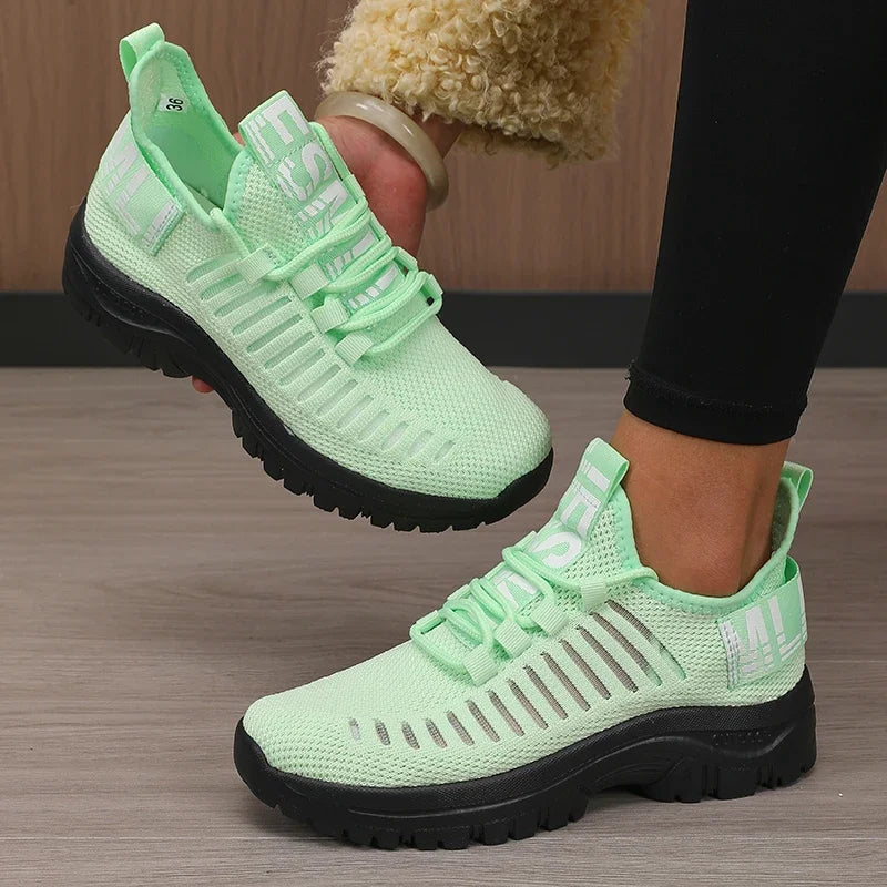 Basket orthopédique femme - Chaussures légères vertes avec détails en noir, vue de près portée par une femme en leggings noirs.