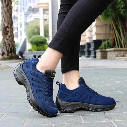 Basket orthopédique femme - Chaussures de sport respirantes en maille bleu marine avec semelle amortissante, portées sur un chemin urbain.