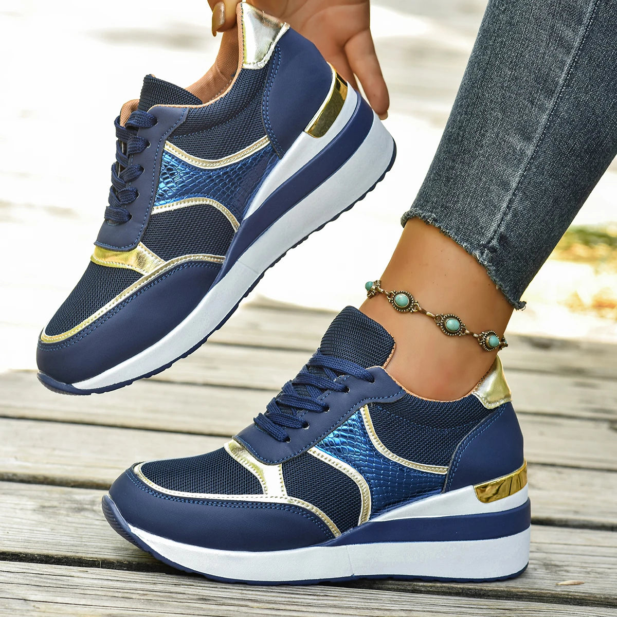 Basket orthopédique femme - Sneakers légères à lacets bleu marine avec détails dorés, portées sur une surface en bois, bracelet turquoise visible