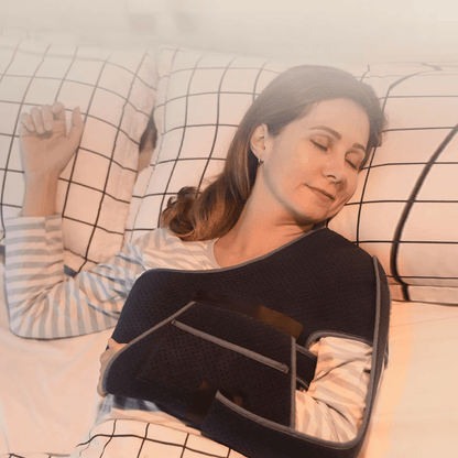 Attelle bras épaule noire en tissu mesh, portée par une femme allongée sur le côté, montrant son confort et son ajustement sur le corps.