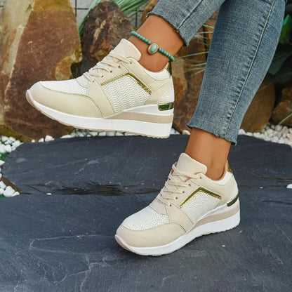 Basket orthopédique femme - Sneakers légères beiges à semelle épaisse, avec détails dorés, portées sur un sol en pierre.