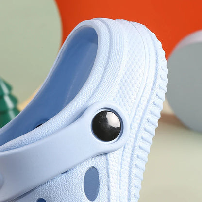 Claquette enfant - Modèle Croks – détail de la fermeture à bouton sur une claquette bleue, en matière imperméable avec texture antidérapante