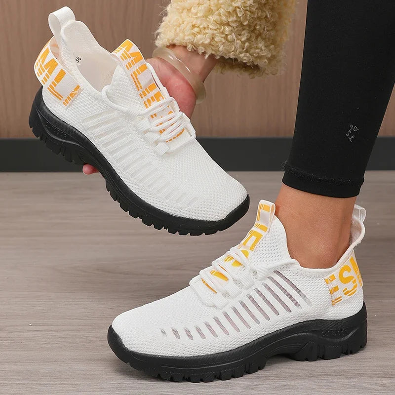 Basket orthopédique femme - Chaussures légères blanches avec lanières jaunes, vue de près portée par une femme en leggings noirs.