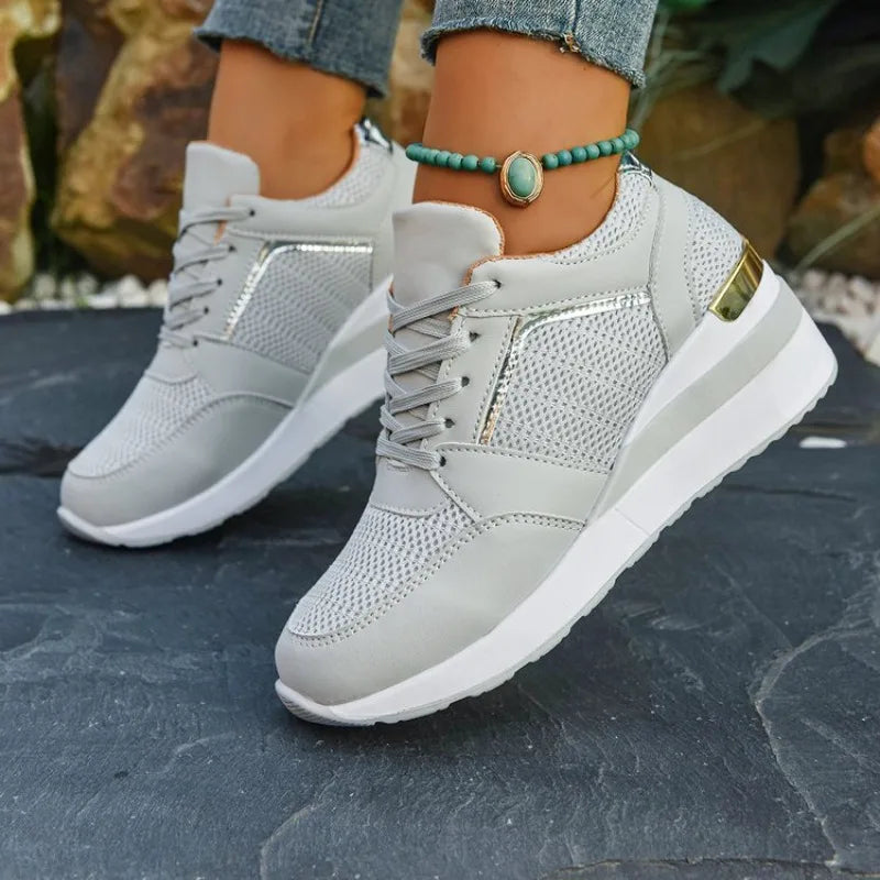 Basket orthopédique femme - Sneakers légères grises à semelle épaisse, portées avec un bracelet sur une terrasse en pierre.