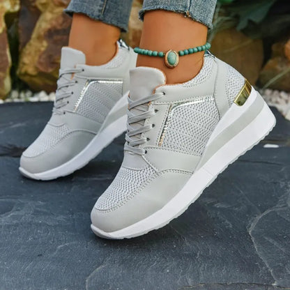 Basket orthopédique femme - Sneakers légères grises à semelle épaisse, portées avec un bracelet sur une terrasse en pierre.