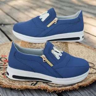 Basket orthopédique femme - Sneakers bleues avec zip doré et semelle blanche, vue de face sur un fond en paille