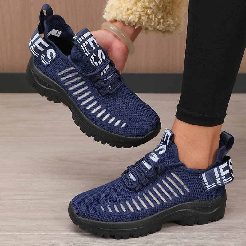 Basket orthopédique femme - Chaussures légères en maille bleu marine avec empiècements noirs, vue de près portée par une femme en leggings noirs.