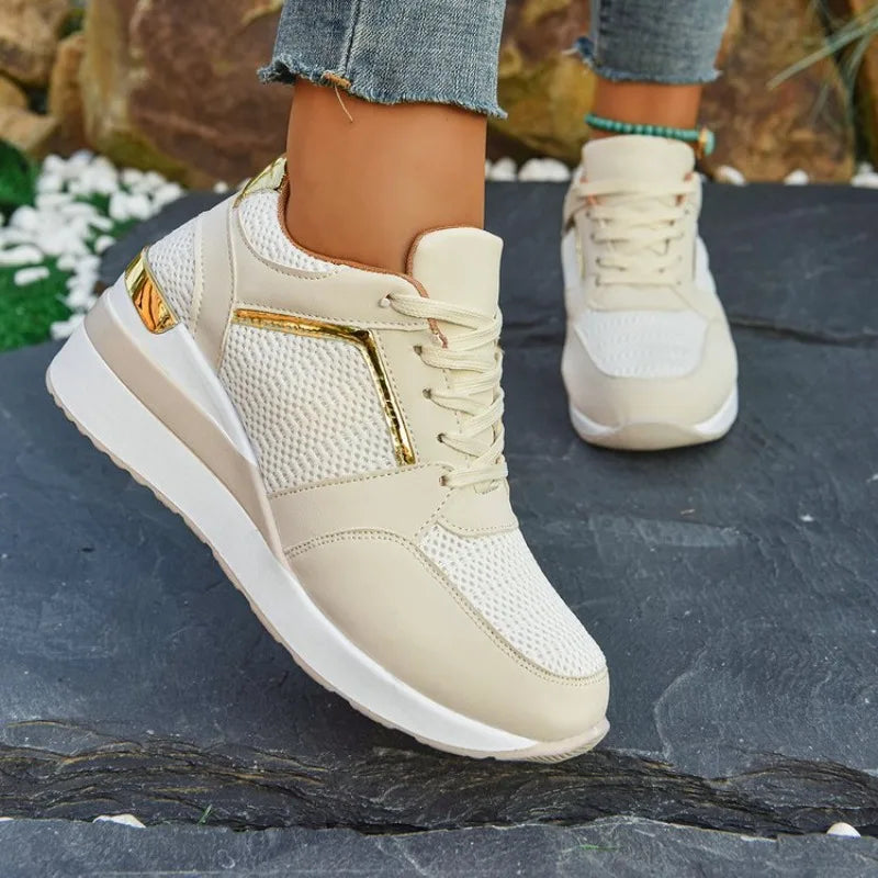 Basket orthopédique femme - Sneakers légères beiges avec détails dorés et semelle épaisse, portées sur un sol en pierre.