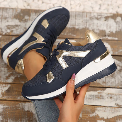 Basket orthopédique femme - Sneakers confortables à semelle épaisse en textile bleu marine avec détails dorés, tenues à la main sur un fond en bois.