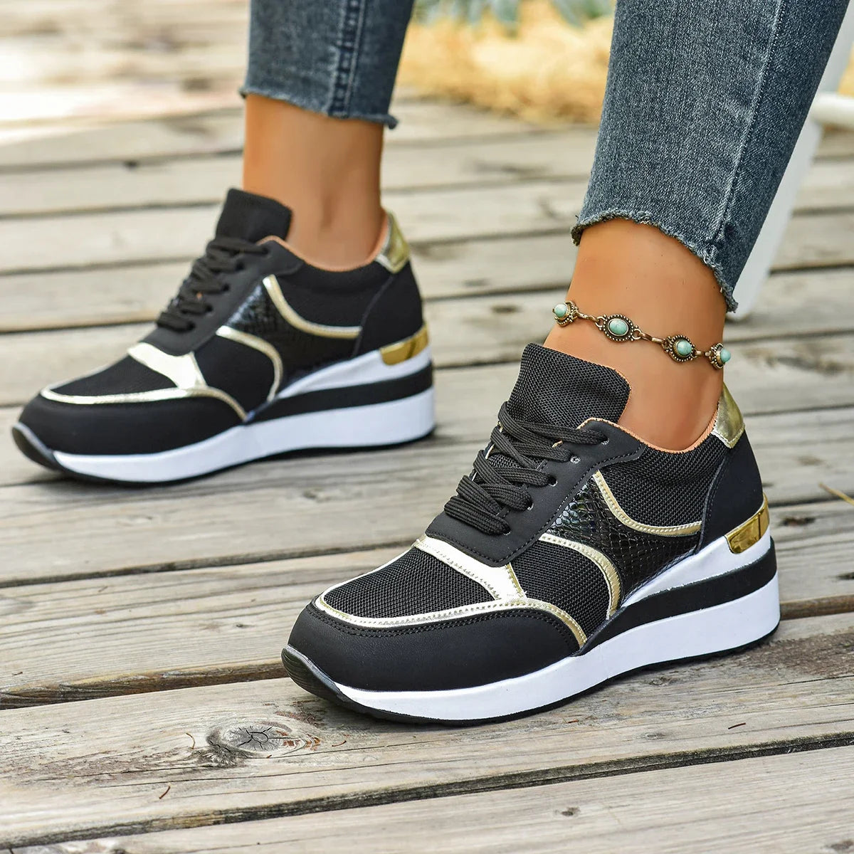 Basket orthopédique femme - Sneakers légères à lacets noires avec détails argentés, portées sur un sol en bois