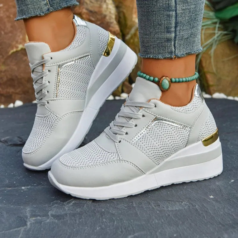 Basket orthopédique femme - Sneakers légères grises à semelle épaisse, portées avec un jean, sur un sol en pierre.