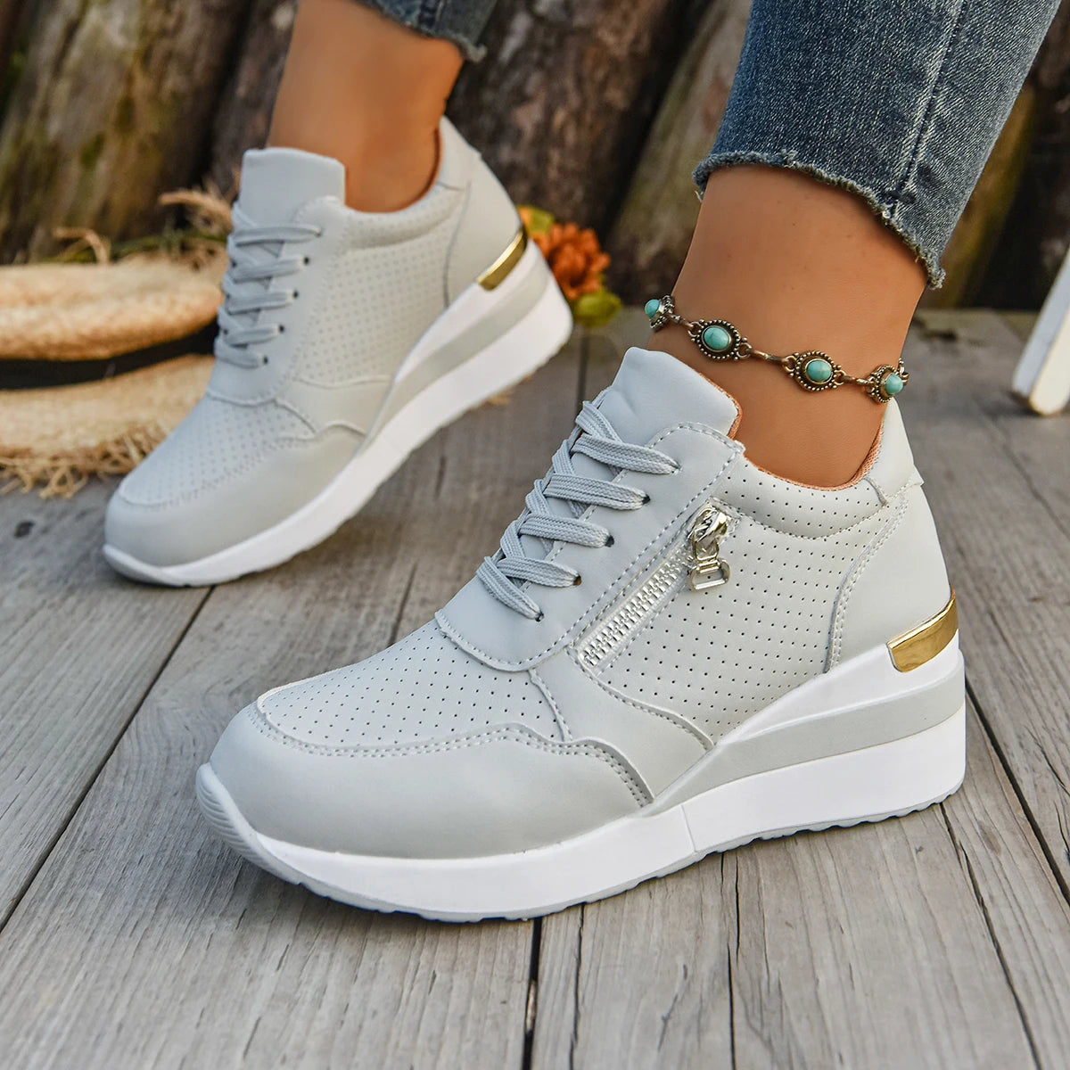 Basket orthopédique femme - Sneakers légères grises à semelle antidérapante avec zip décoratif, portées sur une terrasse en bois.