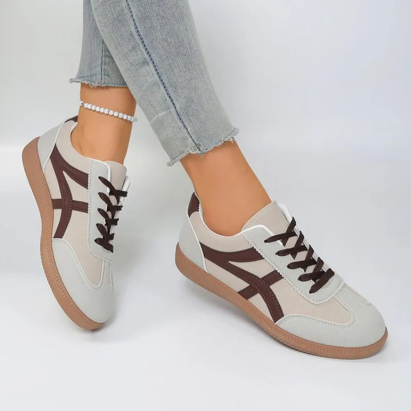 Basket orthopédique femme - Sneakers blanches avec détails marron, portées avec un jean, vue de côté mettant en avant la semelle ergonomique.