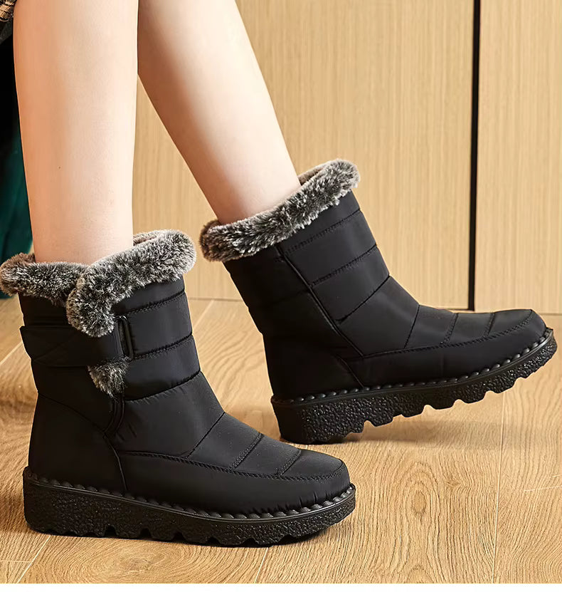 Bottines de Neige Femme : Élégance et Performance Hivernale – Bottines noires avec bordure en fourrure grise, vue latérale sur un sol en bois