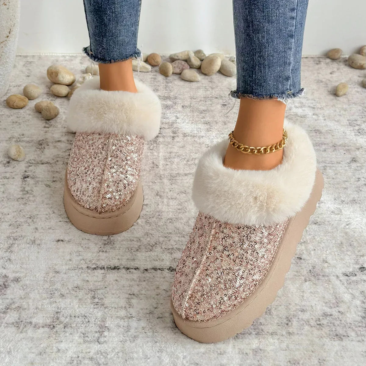 Chaussons Femme Tendance - Peluche Courte Douce - Style Élégant avec paillettes roses et fourrure blanche, portés avec un jean sur un sol en pierre.