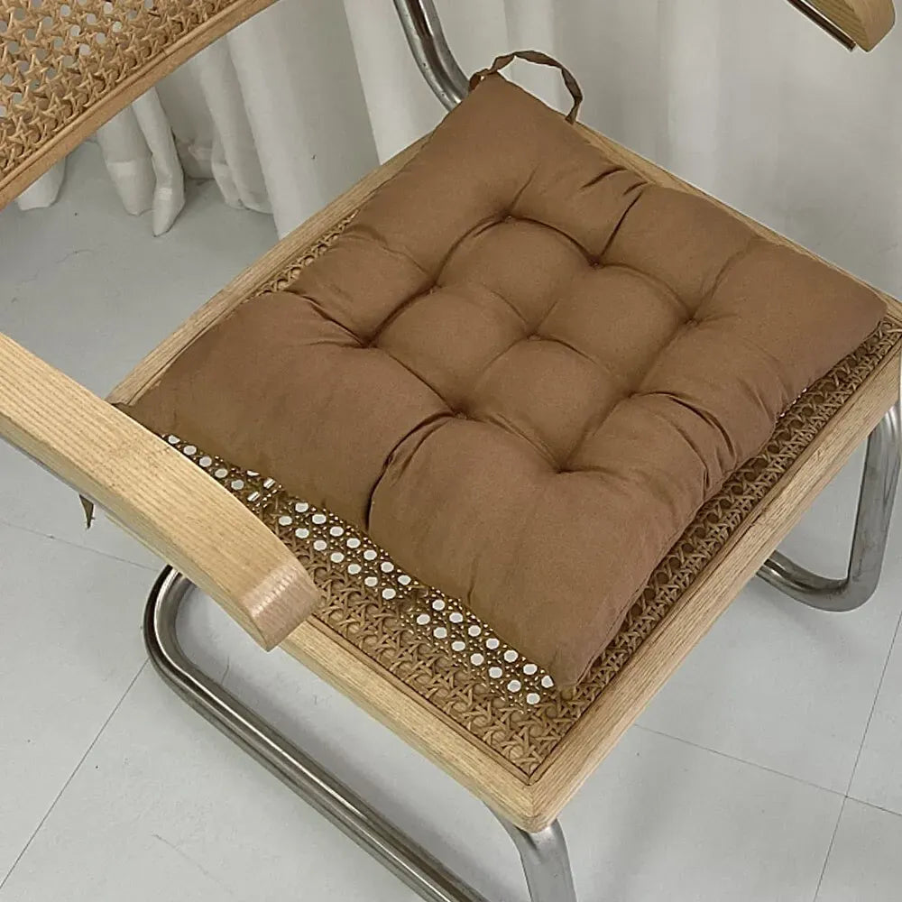 Coussin Orthopédique pour Position Assise – coussin marron sur une chaise en bois avec texture rembourrée et coutures visibles