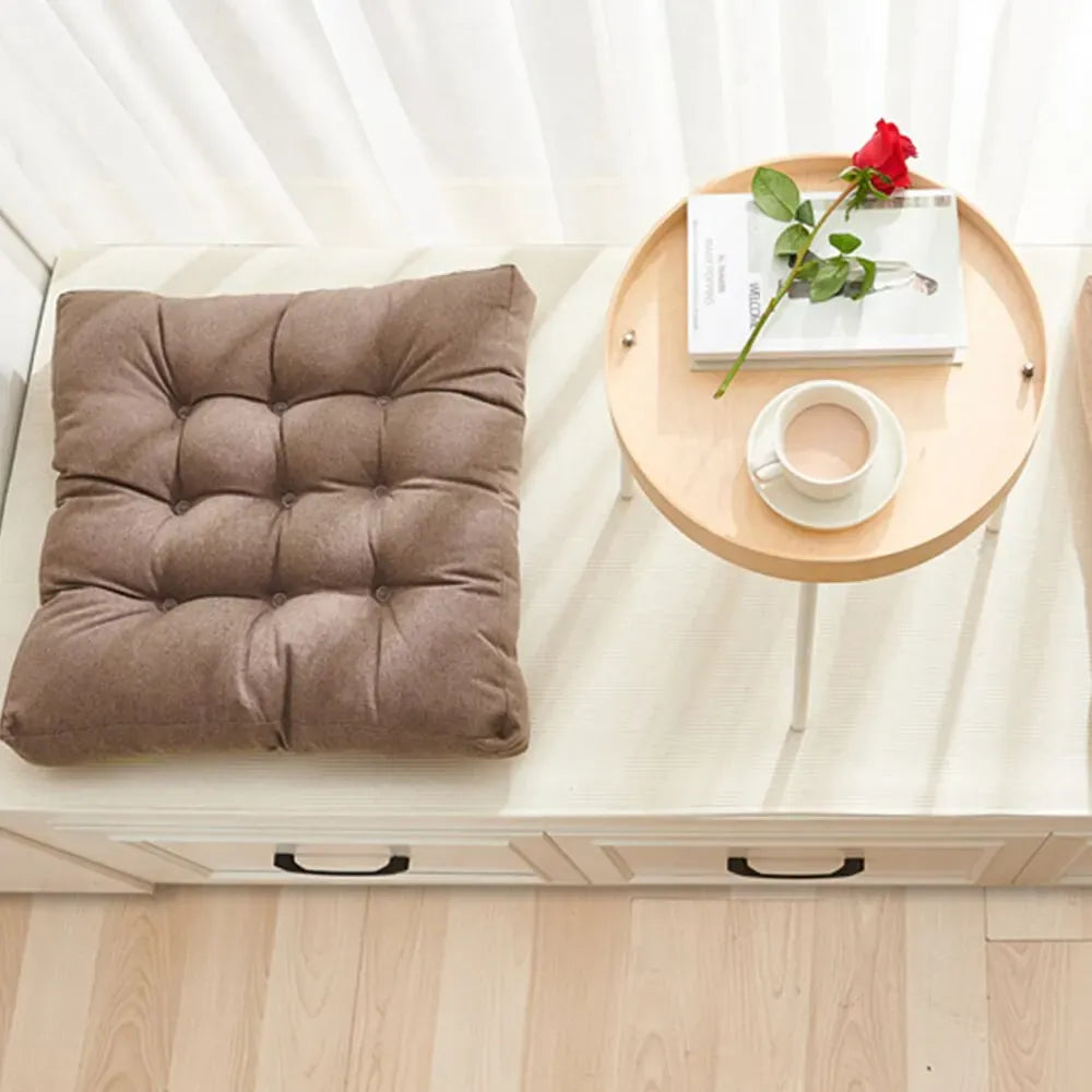 Coussin Orthopédique pour Position Assise – coussin marron capitonné sur un banc en bois avec une tasse et une rose