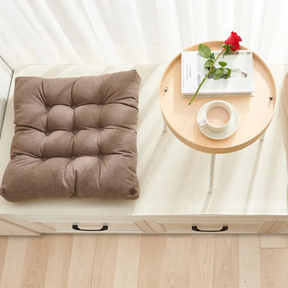 Coussin Orthopédique pour Position Assise – coussin marron capitonné sur un banc en bois avec une tasse et une rose