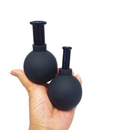 Lot de 4 ventouses anti-cellulites noires en silicone, montrant deux tailles dans une main, avec un design ergonomique.